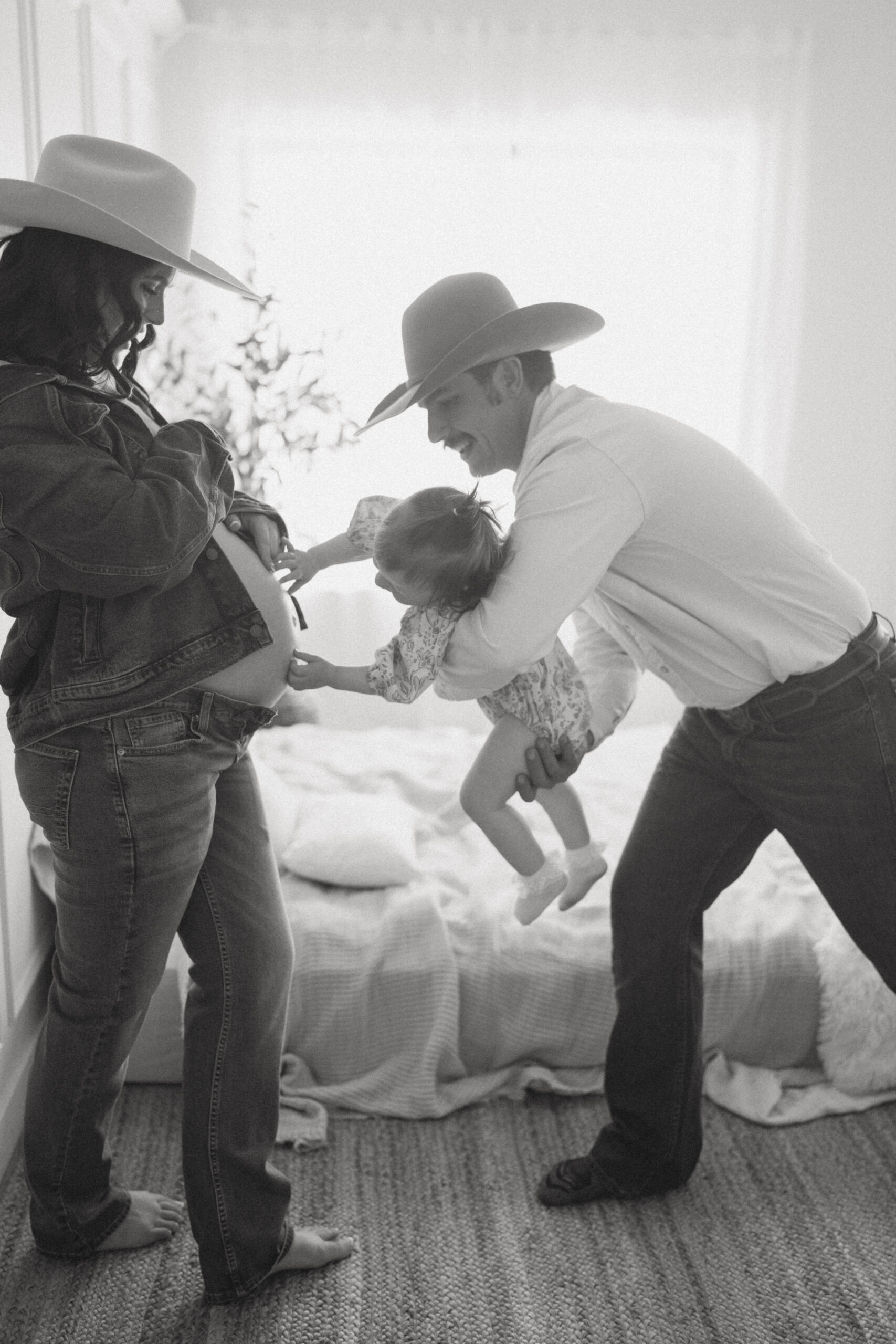 western family pregnant with baby posing with toddler touching moms bump