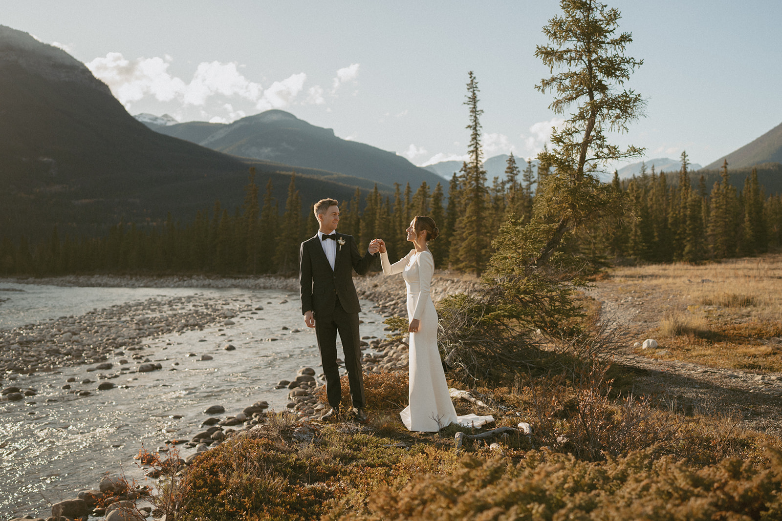 Bride and Groom smiling at each other near a river in jasper national park