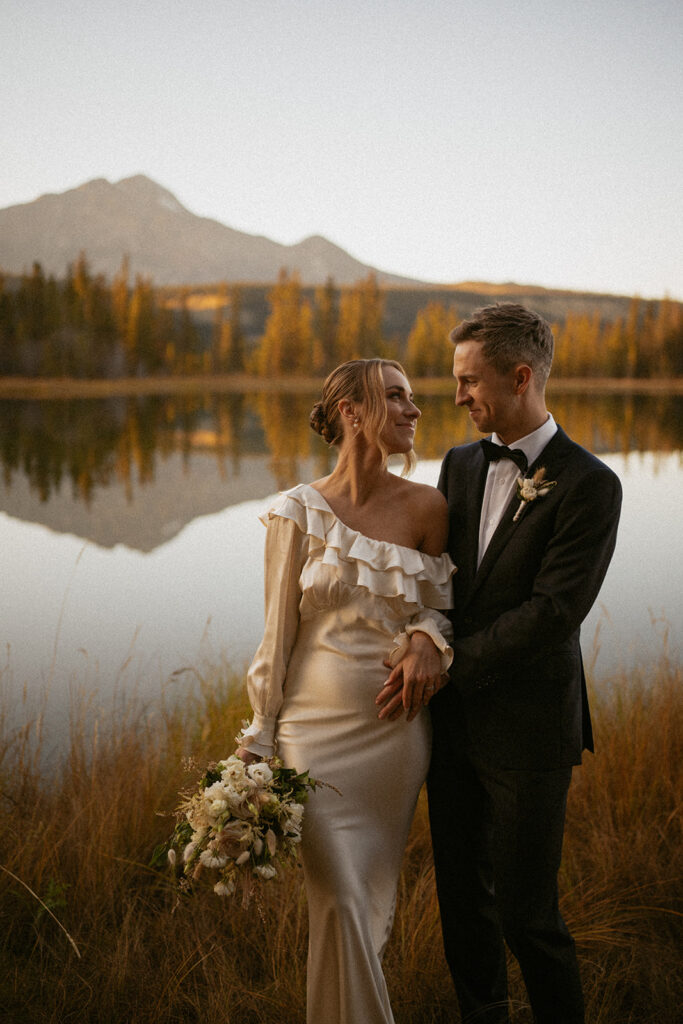 Bride and Groom smiling at each other in front of patricia lake jasper national park