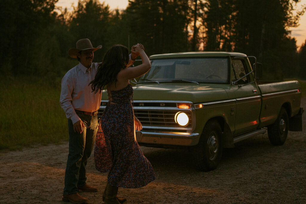 Western Couple Dancing in the Headlights of their Old Green Ford Truck at Dusk on a Dirt Road