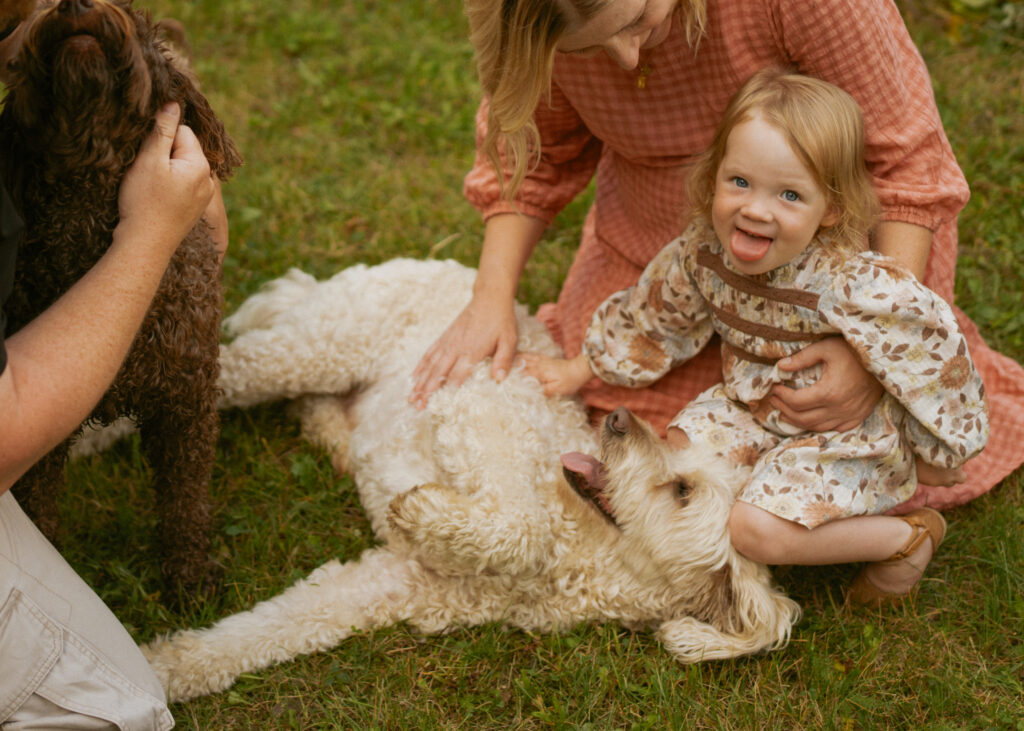 Family Photo with young daughter petting the family dog and laughing