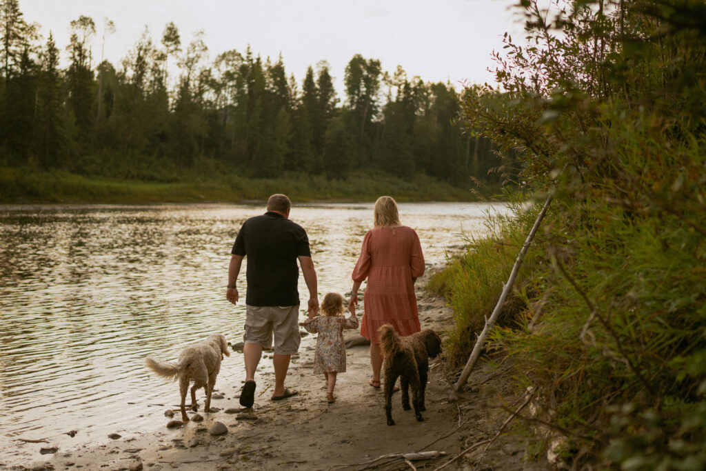 family photo of 4 with their dogs on the river at sunset