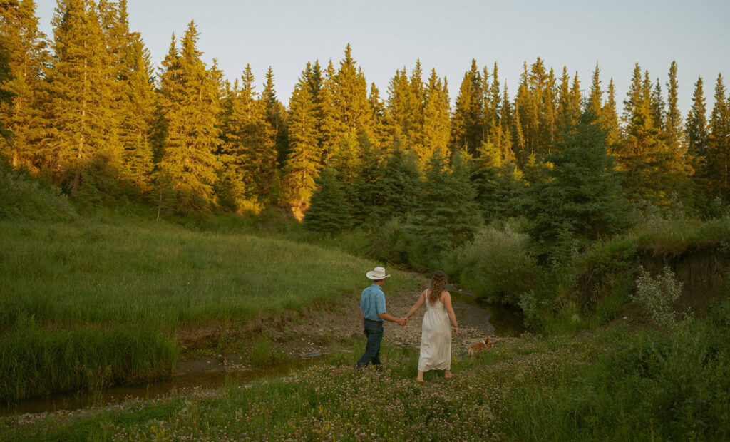 couple walking together holding hands near a river at sunset