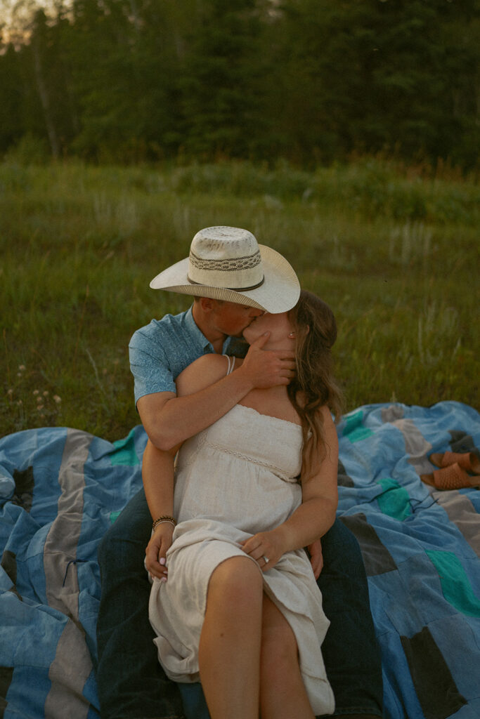 couple kissing at sunset on a picnic blanket