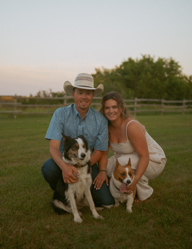 couple smiling at camera with their dogs at sunset