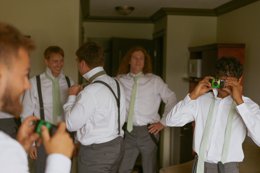 Groomsmen laughing and getting ready with cameras at a Hinton Alberta wedding.