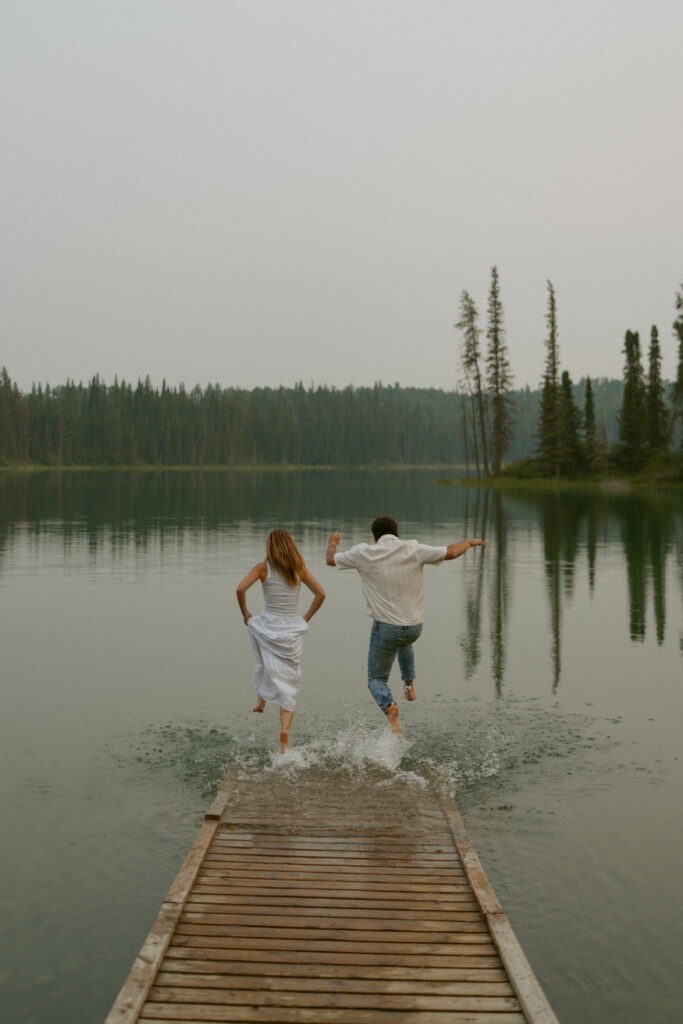 Adventurous couple jumps in lake during photoshoot by Edmonton wedding photographer.