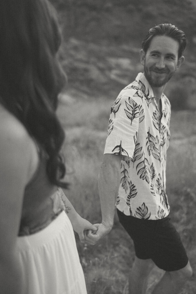 Black and white candid of couple walking hand-in-hand, documented by Drumheller wedding photographer.