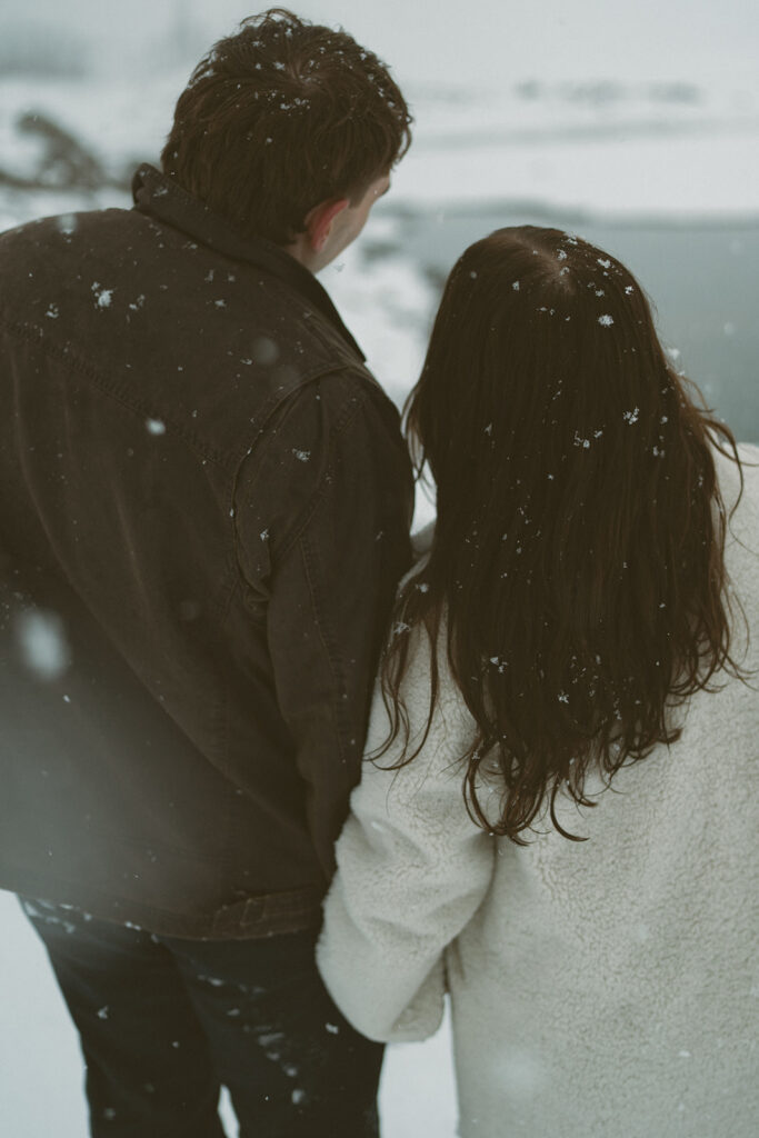 Snow falling on couple’s hands during Jasper engagement session