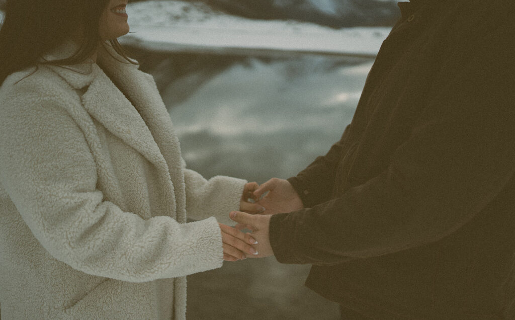 Couple pausing together by water in snowy mountain landscape