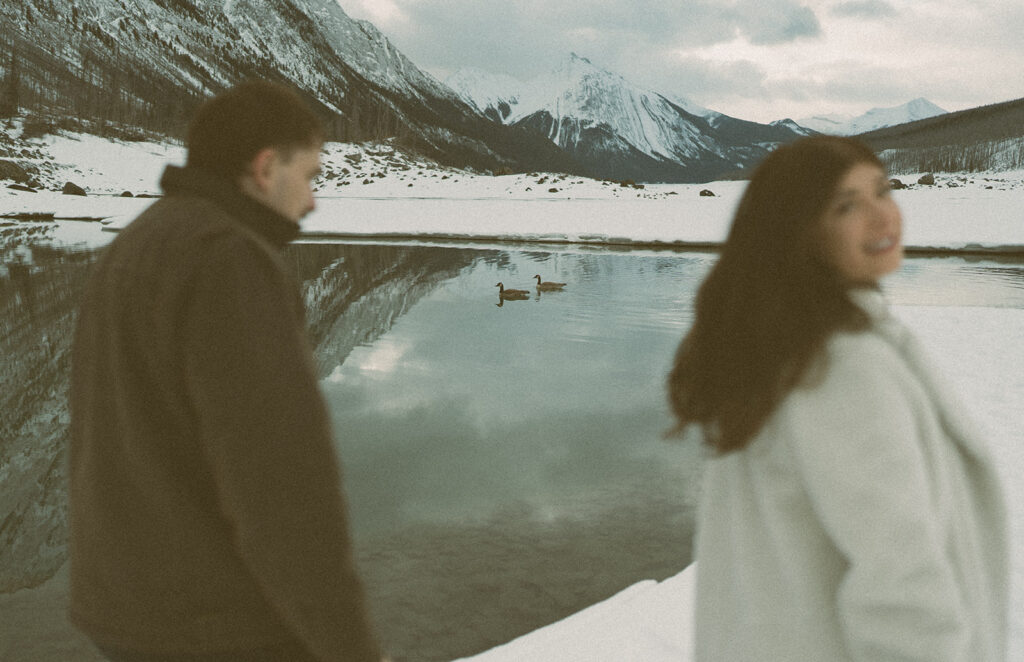 Couple with geese on Medicine Lake during snowy engagement session