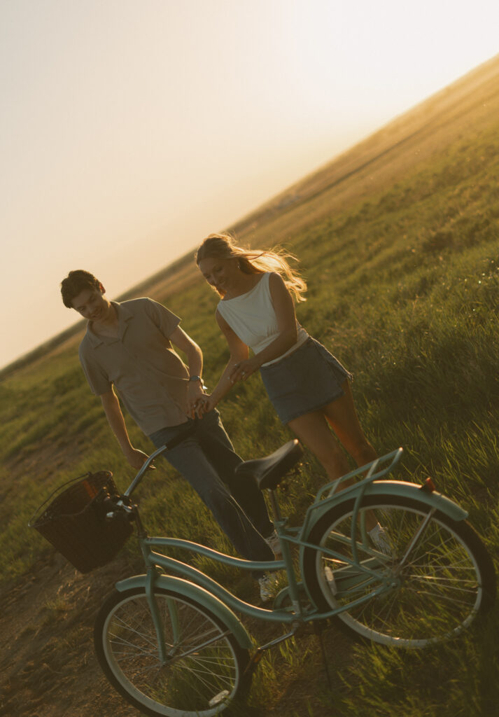 Young couple laughing together while riding bikes during a storytelling engagement session in Lloydminster.