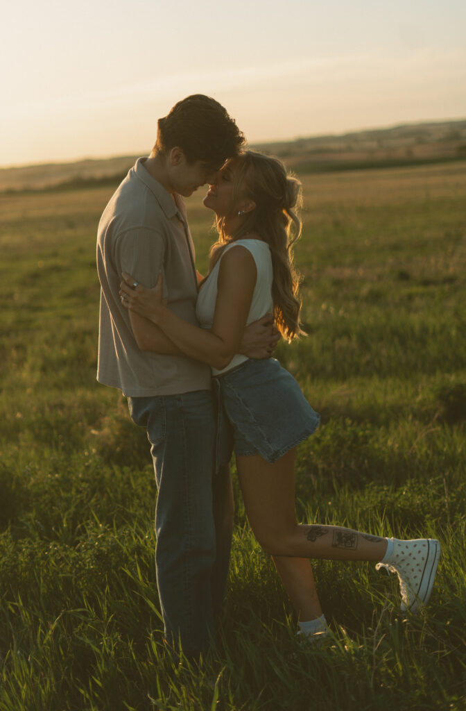 Couple embracing in warm sunset light during a nostalgic prairie couples session.