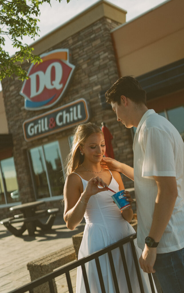 Couple laughing together over ice cream during a playful engagement session in Alberta.