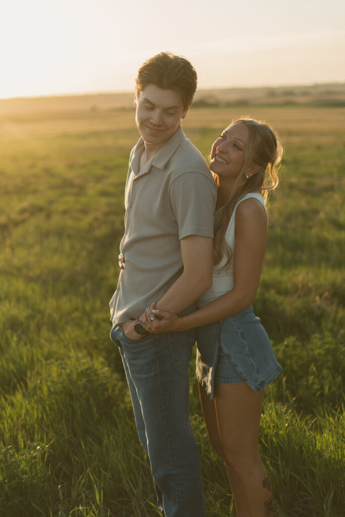 Couple embracing in warm sunset light during a nostalgic prairie couples session.