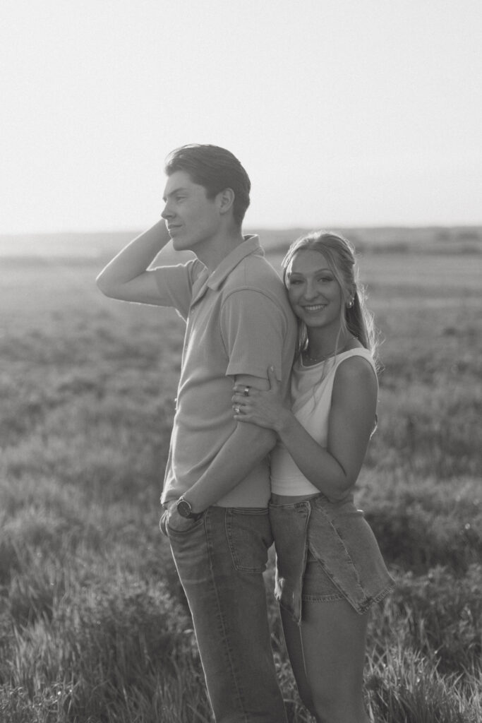 Couple embracing in warm sunset light during a nostalgic prairie couples session.