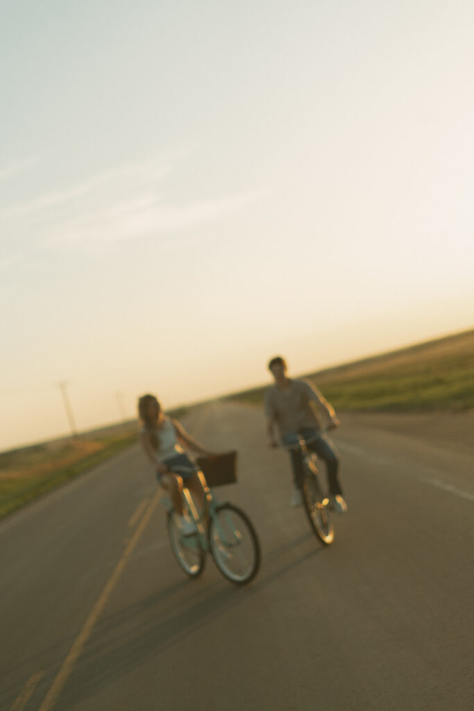 Young couple laughing together while riding bikes during a storytelling engagement session in Lloydminster.