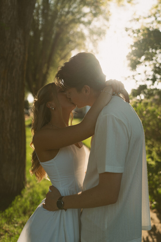 Playful engagement photo of a couple walking through a tree-lined neighborhood in Lloydminster.