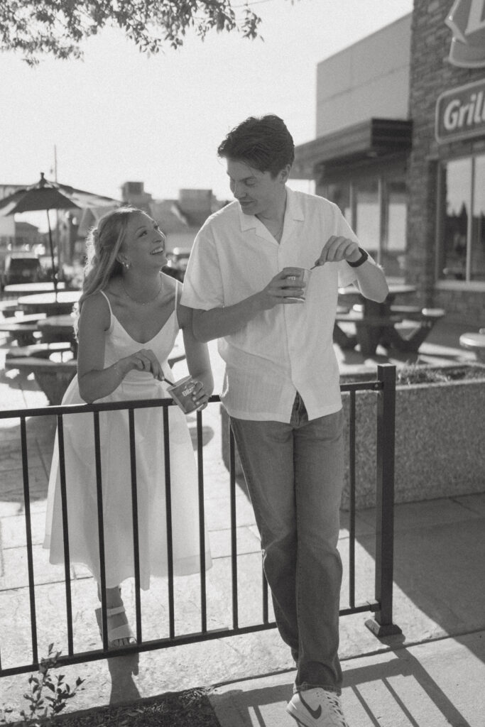 Couple laughing together over ice cream during a playful engagement session in Alberta.