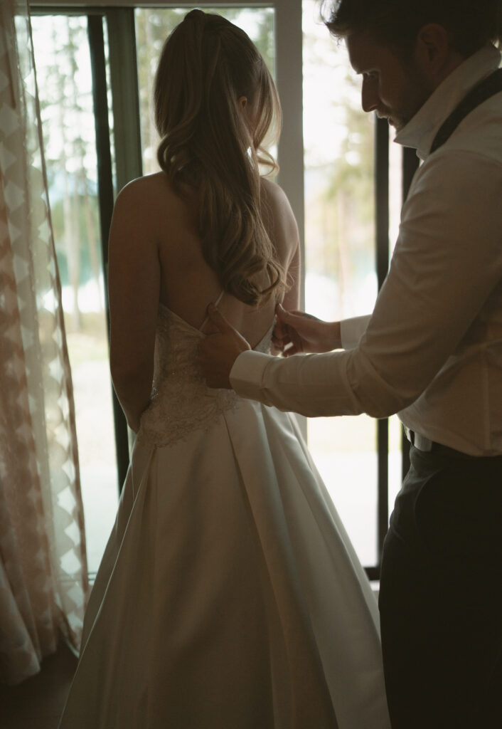Bride and groom helping each other get ready before their Jasper National Park wedding.