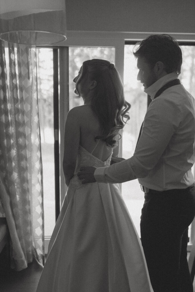 Bride and groom helping each other get ready before their Jasper National Park wedding.