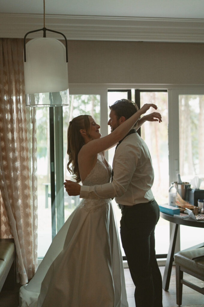 Bride and groom helping each other get ready before their Jasper National Park wedding.